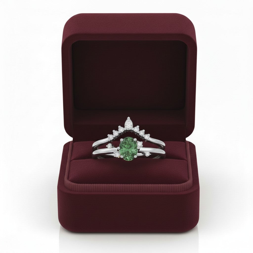 LUMIOR Amara™ 18K gouden moissanite ringenset met groene ovalen steen en diamanten, in een bordeauxrode geschenkdoos.