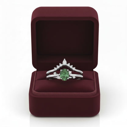 LUMIOR Amara™ 18K gouden moissanite ringenset met groene ovalen steen en diamanten, in een bordeauxrode geschenkdoos.