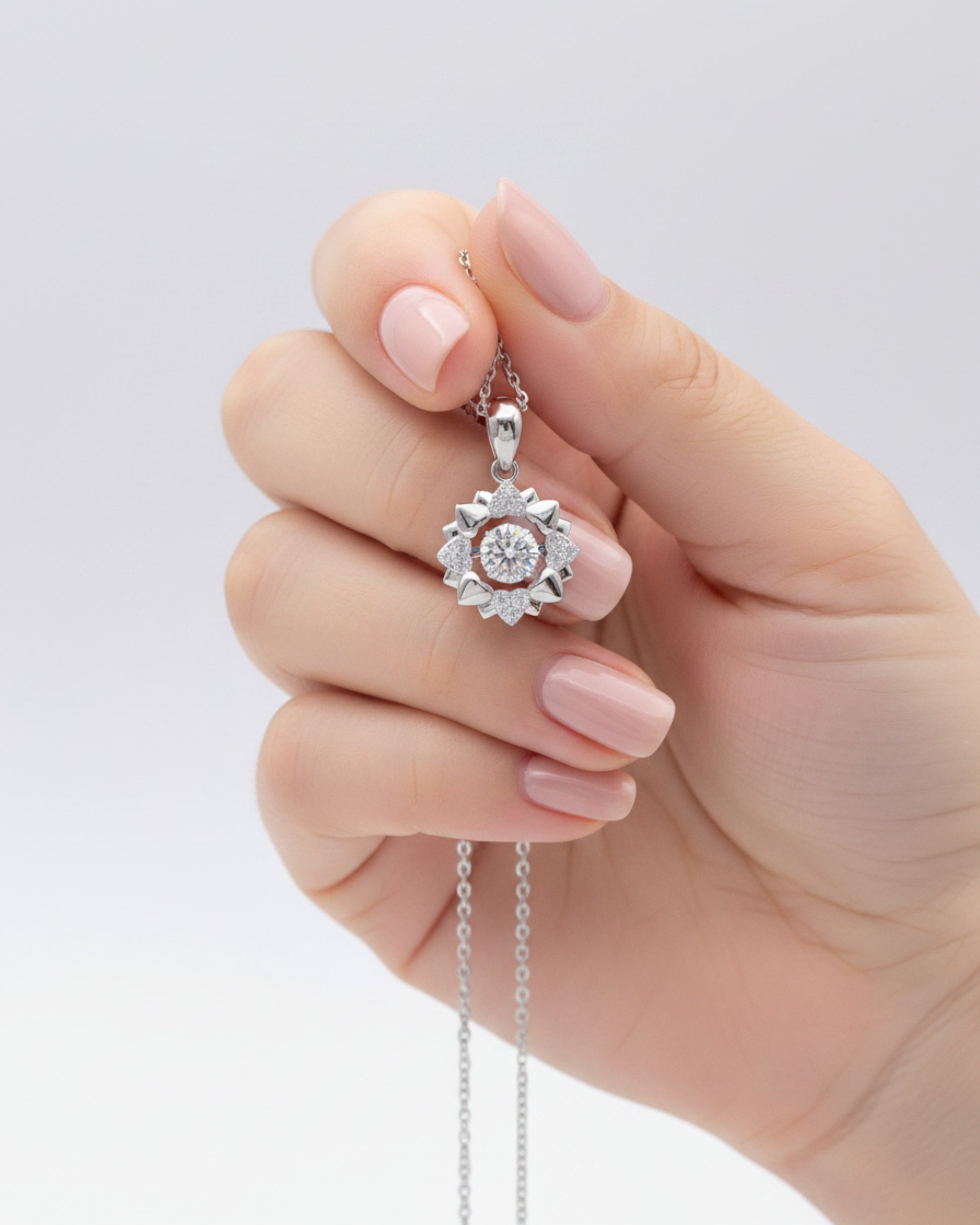 LUMIOR Blossom Aura ketting met 0,5 karaat moissaniet bloemhanger in 925 sterling zilver vastgehouden in een hand.