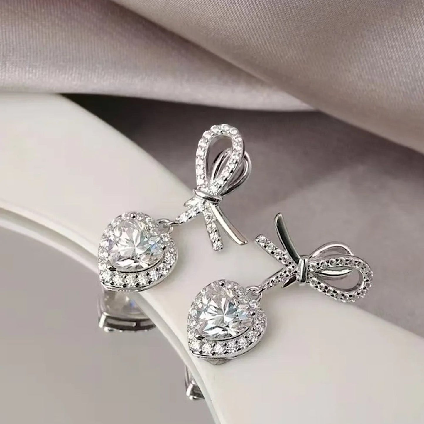 LUMIOR Amour Solitaire 2 karaat hartvormige moissanite oorbellen met strikdetail en platina plating.