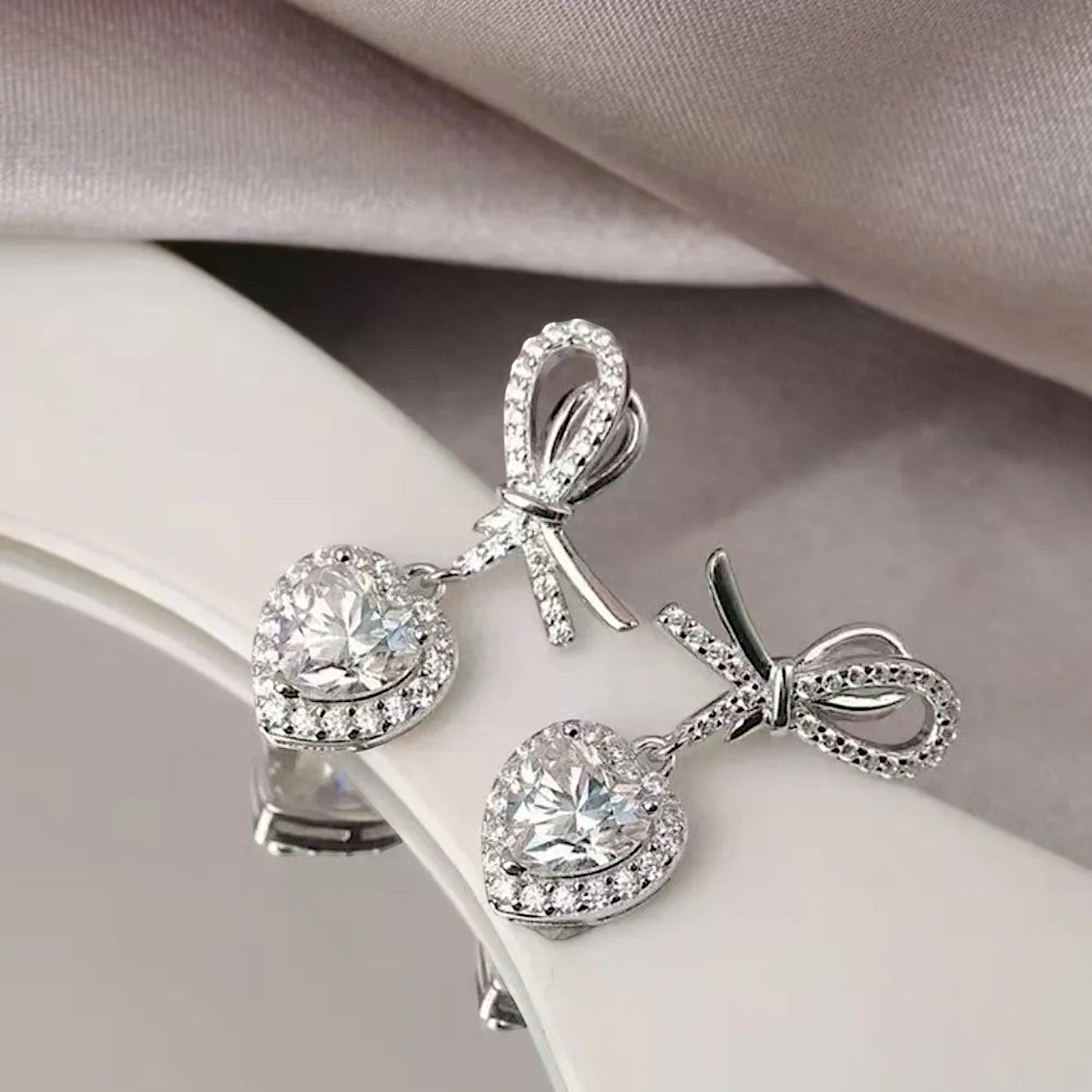 LUMIOR Amour Solitaire 2 karaat hartvormige moissanite oorbellen met strikdetail en platina plating.