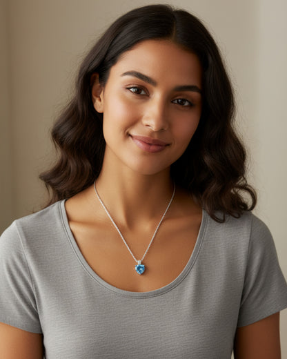 Vrouw draagt een LUMIOR hartvormige ketting van 925 sterling zilver met een blauwe zirkon hanger.