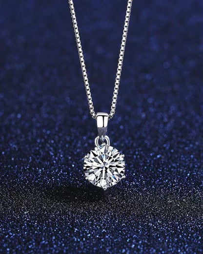LUMIOR minimalist 1 karaat moissanite hanger ketting van 925 sterling zilver tegen een donkerblauwe achtergrond.