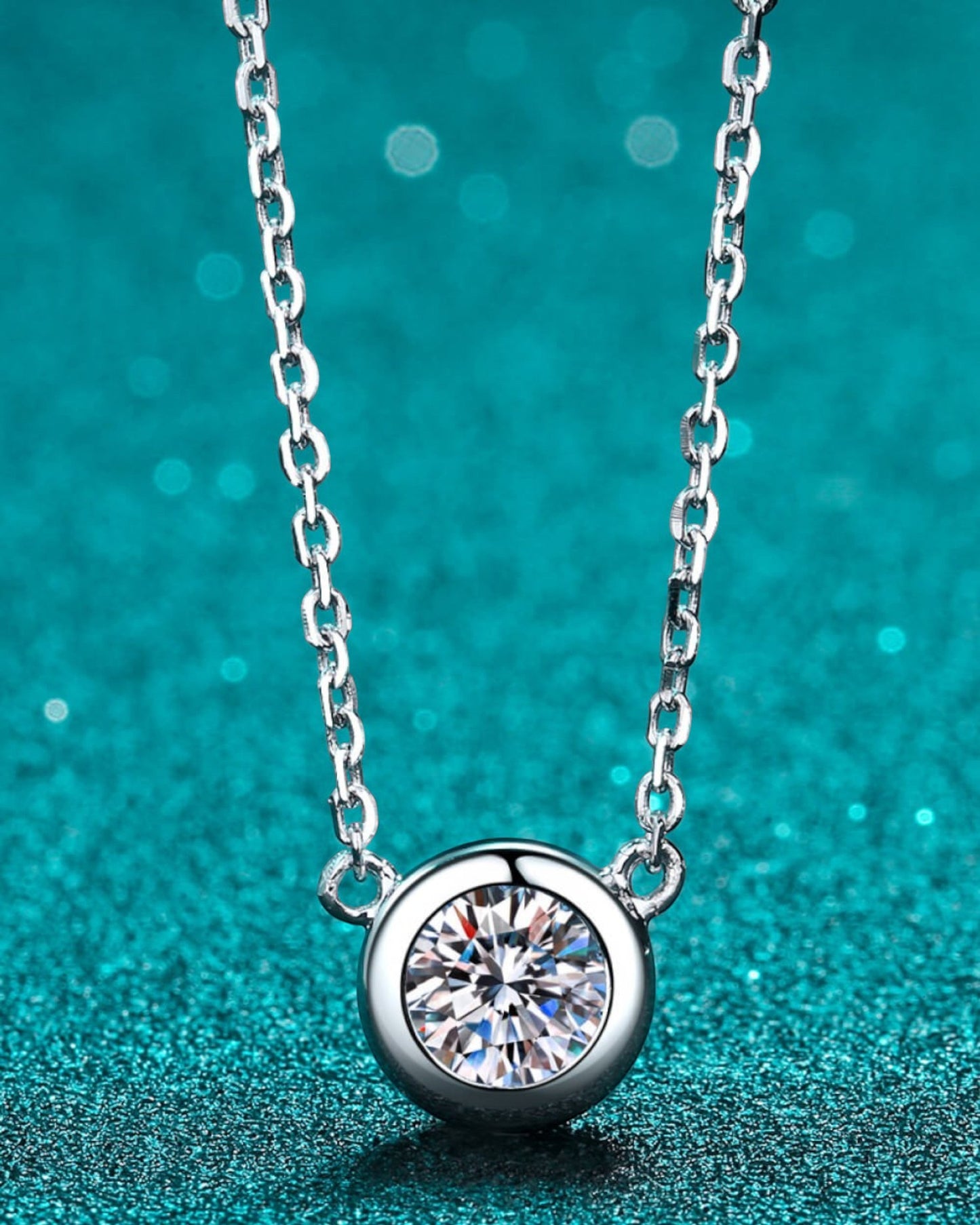 LUMIOR 1 karaat ronde moissanite hanger ketting van 925 sterling zilver met rhodium afwerking op blauwe achtergrond.