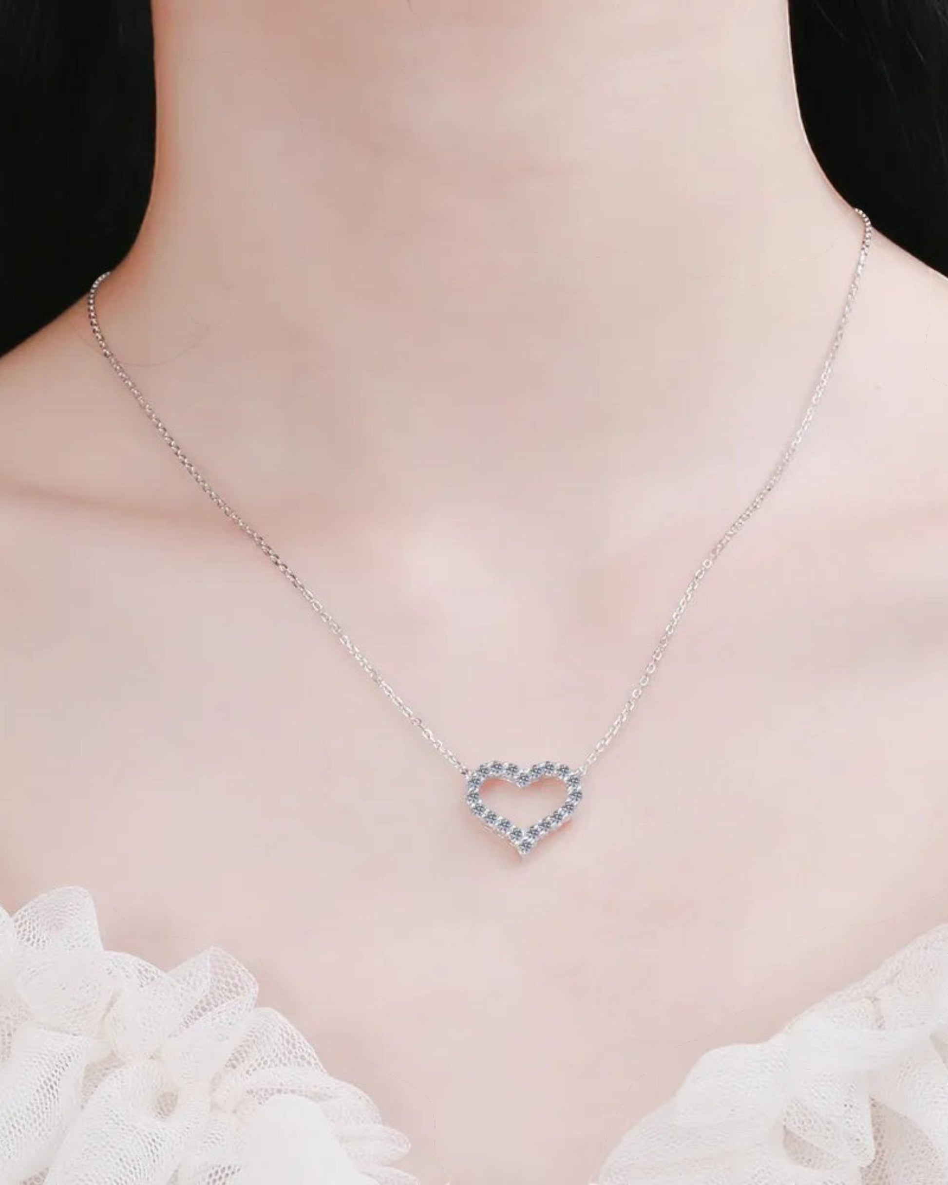 LUMIOR hartvormige ketting van 925 sterling zilver met 0,6 karaat moissanite stenen gedragen om de hals.