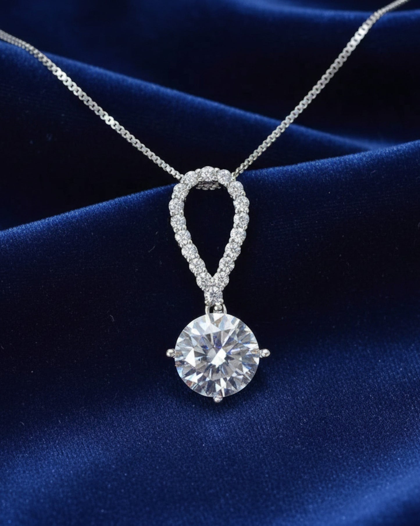 LUMIOR 5 karaat moissanite ketting met peervormige hanger in 925 sterling zilver op een blauwe fluwelen achtergrond.