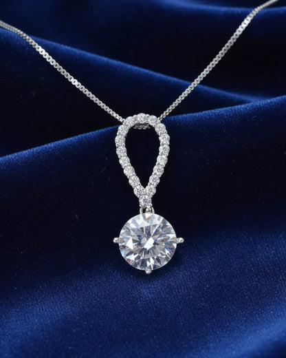 LUMIOR 5 karaat moissanite ketting met peervormige hanger in 925 sterling zilver op een blauwe fluwelen achtergrond.