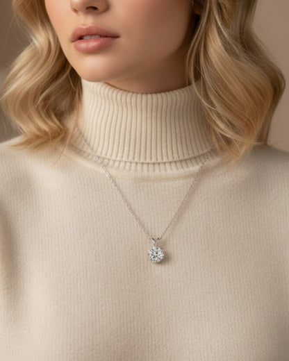 LUMIOR 1 karaat moissanite solitaire hanger in 925 sterling zilver gedragen door een vrouw met een beige coltrui.