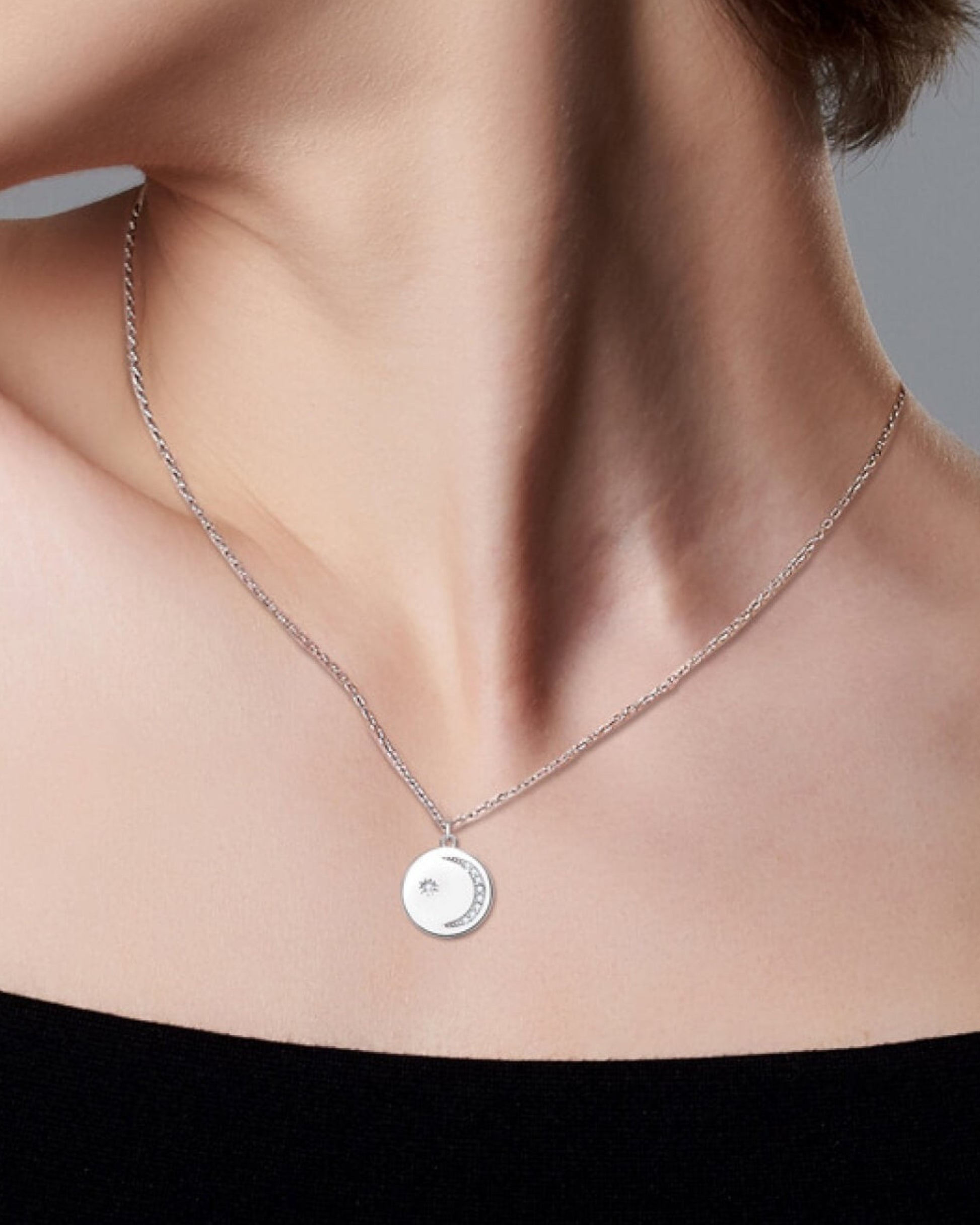 LUMIOR ronde zilveren ketting met 0.095 ctw moissanite hanger gedragen door een model.